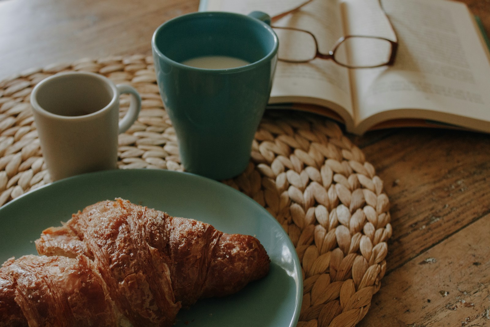 a blue plate topped with croissants next to a cup of coffee