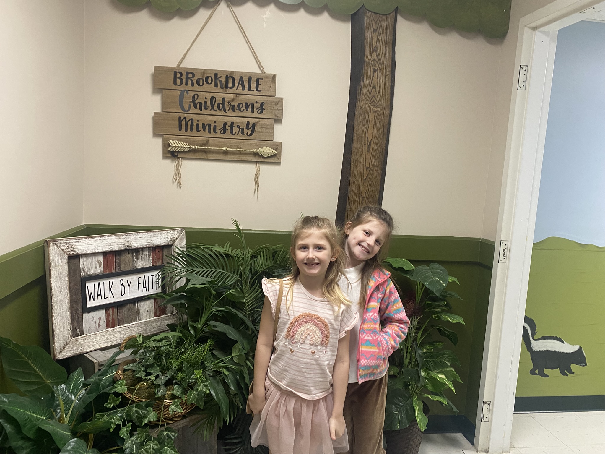 girl's left hand wrap around toddler while reading book during golden hour